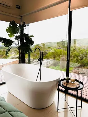 a bath tub in a room with a large window at Surrexit Suites in Tanti