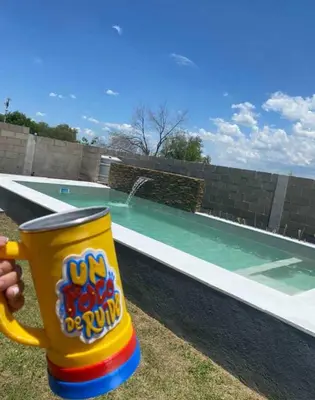 a persons hand holding a cup next to a swimming pool at Casa Francesca in Villa Carlos Paz