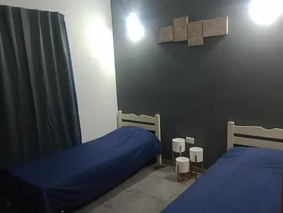 a bedroom with two beds and a cross on the wall at Casa Francesca in Villa Carlos Paz