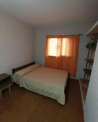 a small bedroom with two beds and a window at Residencial El aromo in Villa Cura Brochero