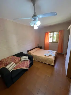 a room with two beds and a couch and a ceiling fan at Residencial El aromo in Villa Cura Brochero