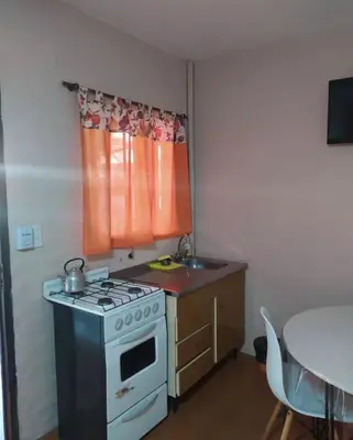 a kitchen with a stove and a sink and a table at Residencial El aromo in Villa Cura Brochero