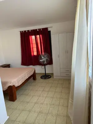 a bedroom with a bed and a window with a fan at Aires de familia in Villa Carlos Paz