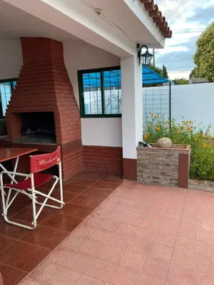 a patio with a brick fireplace and a red chair at Aires de familia in Villa Carlos Paz