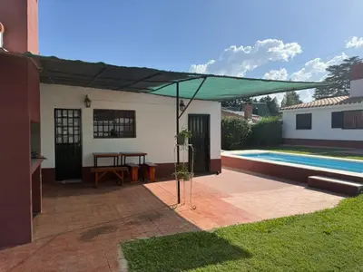 a patio with a green canopy over a swimming pool at Aires de familia in Villa Carlos Paz