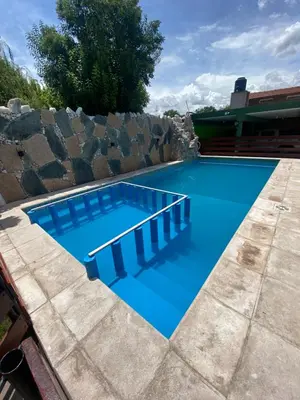 a blue swimming pool with a rock wall around it at Casa Familiar Centrica Abdulle in Villa Cura Brochero