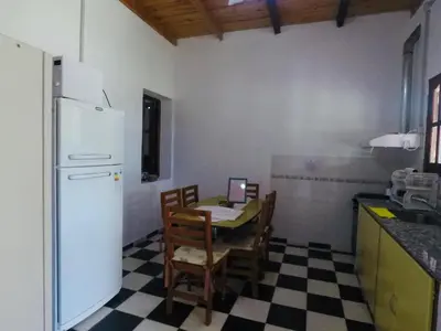 a kitchen with a table and a white refrigerator at Cabañas Quinta El Tesoro in Villa Dolores
