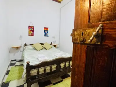 a small bedroom with a bed with a wooden door at Cabañas Quinta El Tesoro in Villa Dolores