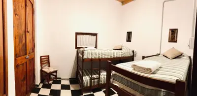 a room with two beds and a chair in it at Cabañas Quinta El Tesoro in Villa Dolores