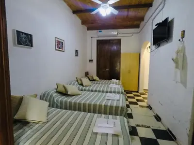 a room with three beds and a ceiling fan at Cabañas Quinta El Tesoro in Villa Dolores