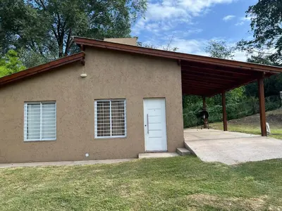 a house with a garage with a dog standing outside at Casa Paz in Santa Rosa de Calamuchita