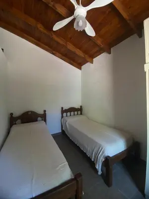 two beds in a room with a ceiling fan at Casa Paz in Santa Rosa de Calamuchita