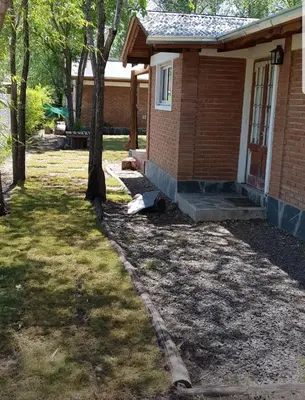 a house with a porch and a tree in the yard at Cabañas Dulce Lugar - Va Ciudad Parque-Calamuchita in Villa Ciudad Parque