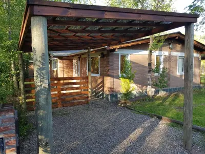 a wooden pergola attached to a house at Cabañas Dulce Lugar - Va Ciudad Parque-Calamuchita in Villa Ciudad Parque