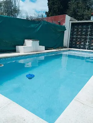 a swimming pool with blue water in front of a fence at La Cautivadora, Potrero de Garay in Potrero de Garay