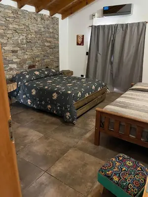 a bedroom with two beds and a stone wall at Casa Isolina in Arroyo de Los Patos