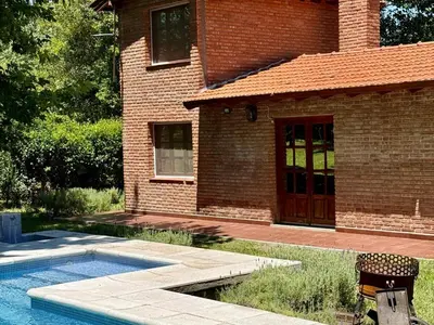 a brick house with a swimming pool in front of it at Cabaña en villa de las Rosas in Villa de Las Rosas
