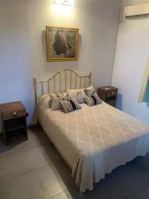 a bedroom with a bed with two night stands and two tables at Casa Isolina II in Arroyo de Los Patos