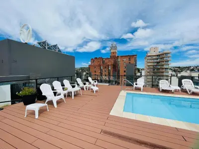 a rooftop deck with white chairs and a swimming pool at Veneto VIII in Villa Carlos Paz