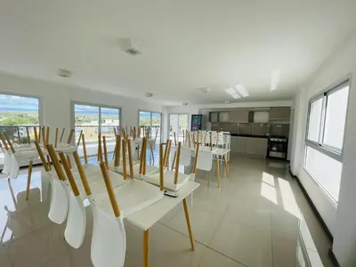a dining room with white chairs and tables and windows at Veneto VIII in Villa Carlos Paz