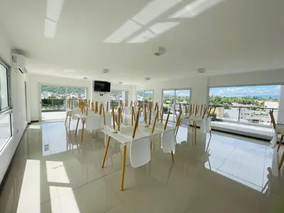 a room with white tables and chairs and windows at Veneto VIII in Villa Carlos Paz