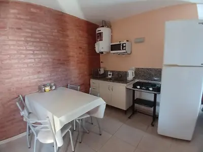 a kitchen with a white table and a white refrigerator at Los tamarindos in Villa Carlos Paz