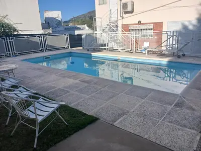 a swimming pool with two chairs in front of a house at Los tamarindos in Villa Carlos Paz
