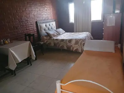 a bedroom with a bed and a table and a brick wall at Los tamarindos in Villa Carlos Paz