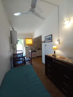 a bedroom with a bed and a desk and a kitchen at El Nogal Mina Clavero in Mina Clavero