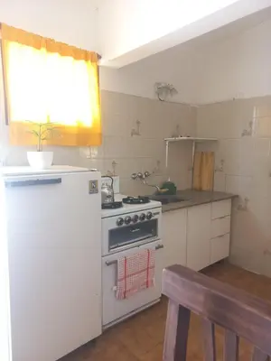 a kitchen with a stove and a white refrigerator at El Nogal Mina Clavero in Mina Clavero