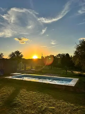 a swimming pool with the sunset in the background at Los algarrobos in Mina Clavero