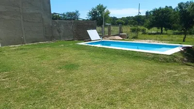 a swimming pool in a yard with a grass field at Los algarrobos in Mina Clavero