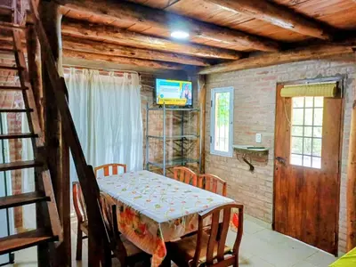 a dining room with a table and chairs and a television at Cabañas La Morena in Panaholma