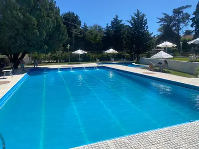 a large blue swimming pool with umbrellas at ALOJATE PREMIUM CARLOS PAZ Oasis in Villa Carlos Paz