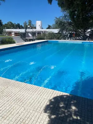 a large swimming pool with blue water at ALOJATE PREMIUM CARLOS PAZ Oasis in Villa Carlos Paz