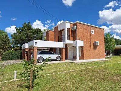 a brick house with a car parked in the driveway at Cabañas Don Pablo in Mina Clavero
