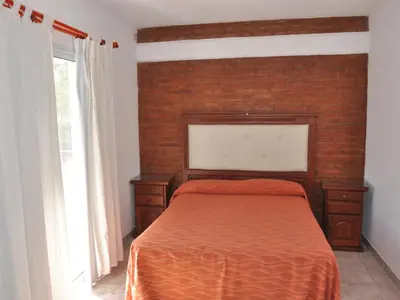a bedroom with a bed with a brick wall at Cabañas Don Pablo in Mina Clavero