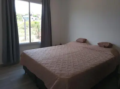 a bed in a bedroom with a large window at Mountain View & Comfort in Villa Santa Cruz del Lago