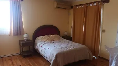 a bedroom with a bed and two night stands and a window at La Casa Del Rio in Villa Santa Cruz del Lago