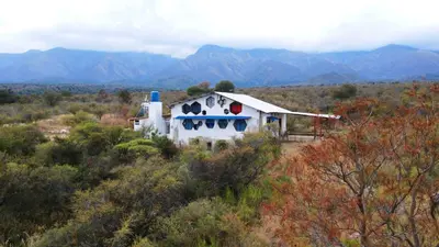 a house in the middle of a field with mountains at Casa de Miel in Los Molles