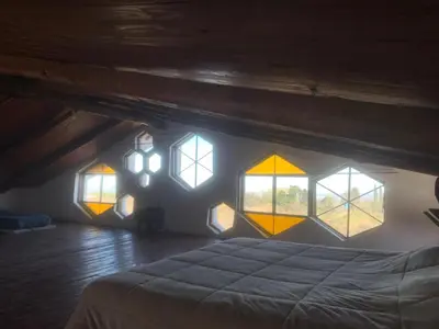 a bedroom with windows and a bed in a attic at Casa de Miel in Los Molles