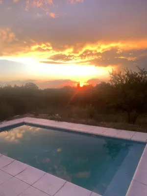 a swimming pool with a sunset in the background at Casa de Miel in Los Molles