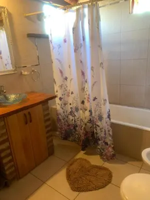 a bathroom with a shower curtain with a sink and a tub at Casa de Miel in Los Molles