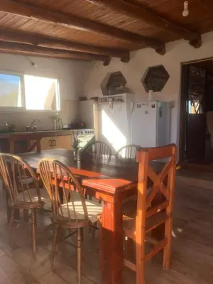 a kitchen with a wooden table with chairs and a refrigerator at Casa de Miel in Los Molles