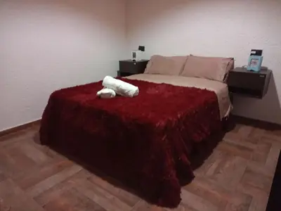 a bedroom with a bed with a red blanket at La Calma in Villa Yacanto