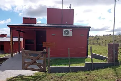 a red building with a fence in front of it at La Calma in Villa Yacanto