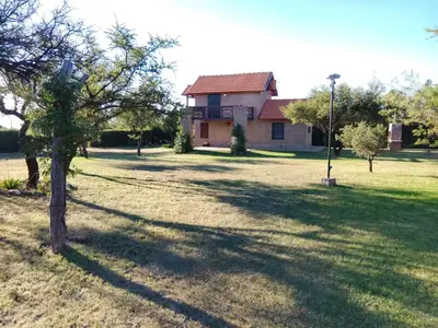a house in a field with a tree in the foreground at Tayimapu in Merlo