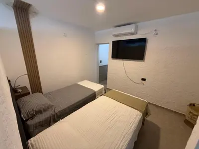 a hotel room with two beds and a flat screen tv at Quintaesencia Suites in Mina Clavero