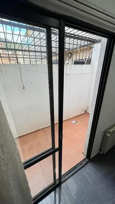 an open glass door with a view of a tennis court at Ailinlduran in Villa Carlos Paz