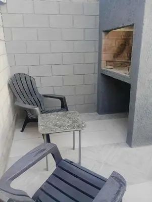 a chair and a bench in front of a fireplace at Casa con pileta privada para 5 in Villa Carlos Paz